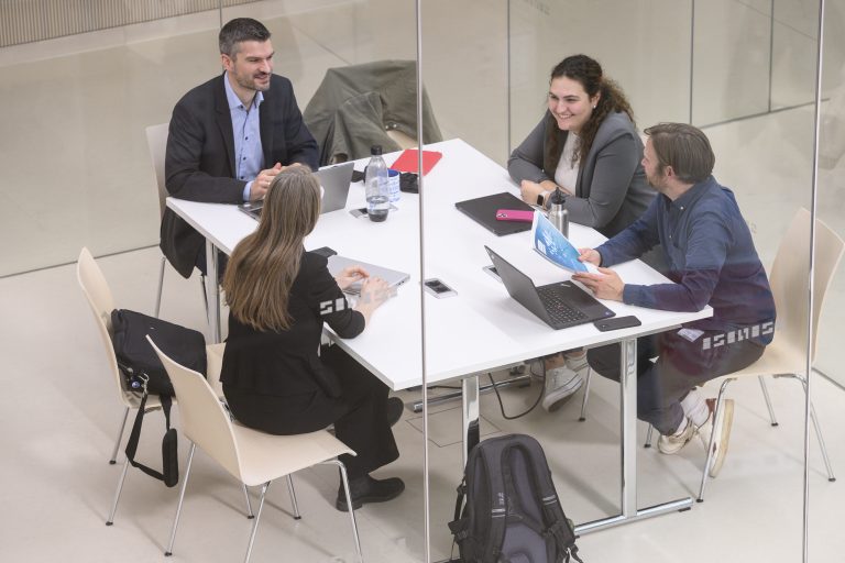 Personen sitzen für ein Meeting in einem Arbeitsraum